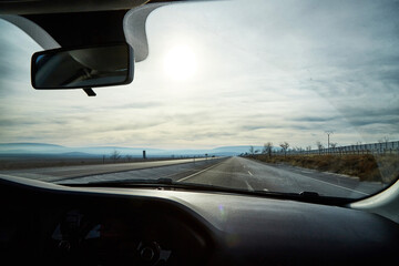 View from car window on the road and strange landscape with a valley, mountains and blue sky with...