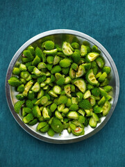 Spiny gourd in small pieces in steel plate on teal background
