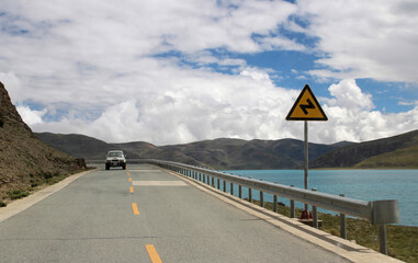 Fototapeta na wymiar View of Yamdrok Lake with a car in a sunny day, Tibet, China