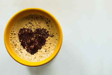 Yellow cup with coffee. Chocolate foam and heart