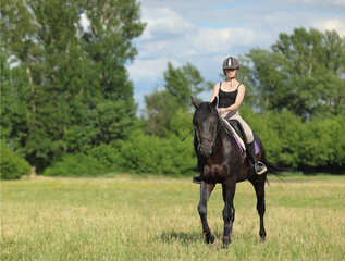 Beautiful equestrian girl ride sports dressage horse in summer forest