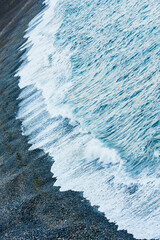 A wave of blue ocean on a beach with black sand. Seascape, view from the top. Russia, far East, Aleutian Bay.