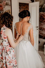 The bridesmaid prepares the bride for the wedding day, helps to button and tie her dress....