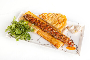 adana kebap.  Turkish Adana Kebab with Vegetables on the Plate.  Traditional oriental Adana kebap and shashlik skewer with tomato and flatbread as top view on a plate with copy space right