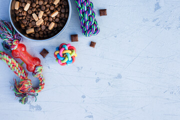 Pet care, playing and training concept. Toys, accessories and dry dog food on the grey background. Top view. Space for a text.