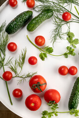 Fresh cucumbers and tomatoes with herbs with water drops.