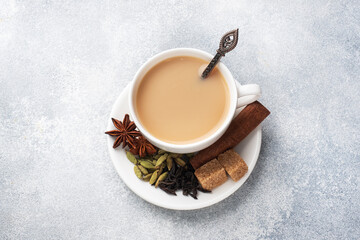 Obraz na płótnie Canvas Indian drink masala tea with milk and spices. Cardamom sticks cinnamon star anise cane sugar. Concrete grey table copy space.