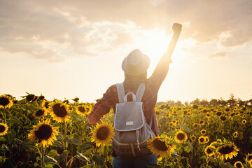 Fototapeta na wymiar Beautiful young girl enjoying nature on the field of sunflowers at sunset