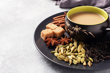 Indian drink masala tea with milk and spices. Cardamom sticks cinnamon star anise cane sugar. Concrete grey table copy space.