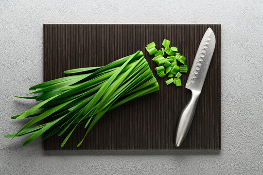 Green onions on a dark cutting board. Allium nutans onion. Top view, dark gray background.