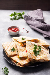 Triangular slices of a Mexican quesadilla with the sauce. The traditional dish of Mexico is tortillas stuffed with meat and vegetables. copy space.