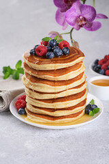 Pancakes with fresh berry and honey on gray background. Healthy breakfast.