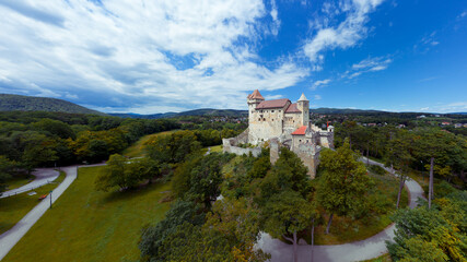 Fototapeta na wymiar Liechtenstein Castle from the sky during sunset. The Liechtenstein Castle, situated on the southern edge of the Vienna Woods, Austria. Breathaking view about a medieval castle.