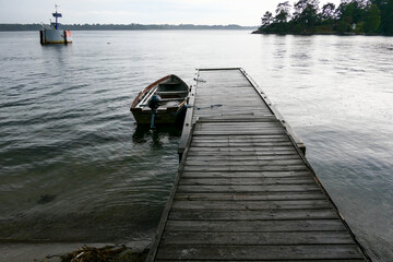 Naklejka premium Sater, Sweden A small dock and a rowboat on Braviken bay in the rain.