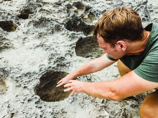Man pulls his hands into mystic dark moon crater. Astrology, astronomy, paranormal activity concept or scary supernatural planet landscape. Dramatic toned natural texture, close view of black coral