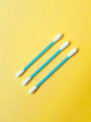 Ear cotton buds are blue on a yellow background. Cosmetology and medicine. Personal hygiene and care.