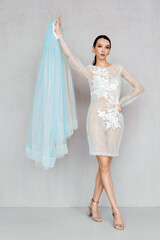 Naklejka premium Beautiful young woman plays with hem of transparent tulle dress with lace