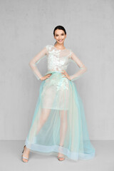Fototapeta na wymiar Beautiful young woman plays with hem of transparent tulle dress with lace