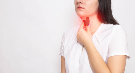 The girl holds her neck with a thyroid gland with her hand on a white background. Thyroid diseases...
