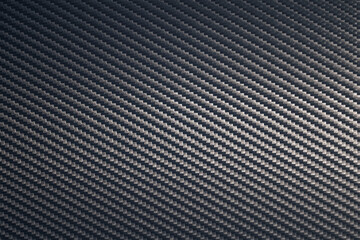 Close up of grey diagonal oriented woven carbon fibre sheet surface.