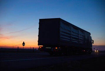 a cargo truck drives on the motorway in the evening against the backdrop of sunset. Truck logistics and transportation concept, copy space for text, business