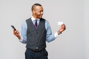 a young African businessman using his smartphone to shop online while holding his credit card