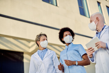 Obraz premium Below view of healthcare workers wearing protective face mask while communicating outdoors.