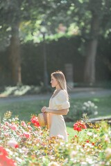Beautiful young woman in a flower garden. Young beautiful woman portrait. Roses. Summer.