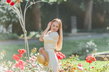 Beautiful young woman in a flower garden. Young beautiful woman portrait. Roses. Summer.