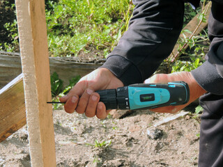 A worker screws a screw driver into a Board to attach it to another Board. A man makes a design on...