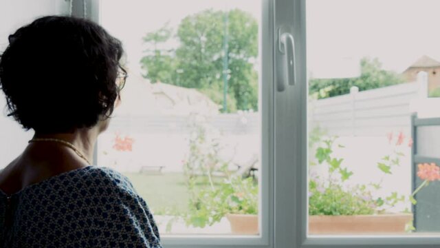 pensive mature woman looks out the window