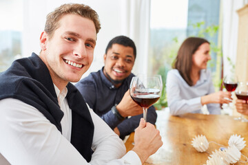 Friends sit together at the table with glass of red wine