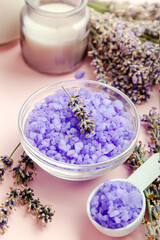 Obraz na płótnie Canvas Lavender violet sea salt with lavender flowers, candle. Lavender bath products Aromatherapy treatment on pink color background. Skincare spa beauty bath cosmetic products for relax.