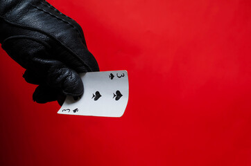 Male hand in leather glove holds playing card.