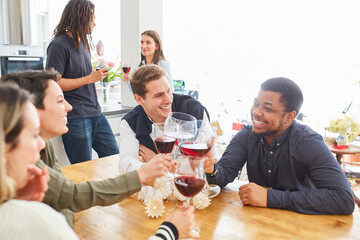 Laughing students drink wine together in shared kitchen
