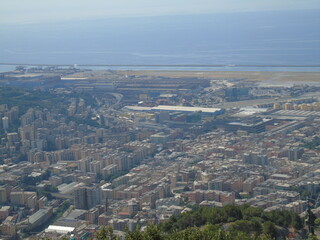 Genova, Italy – 07/30/2020: Beautiful scenic aerial view of the city, port, dam, sea, Cristoforo Colombo airport runway, containers shipping terminal, Pra, Voltri, and Sestri promontory from Monte Gaz