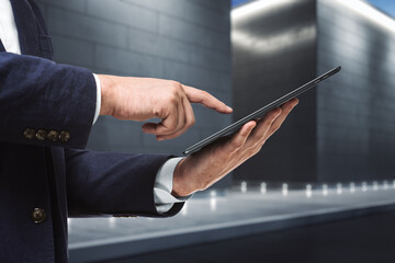 Man using digital tablet near the exterior of the business center at night, close up. Technology concept