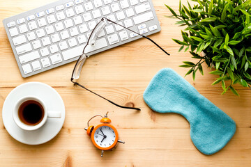 insomnia at work. Sleep mask on wooden office desk top view