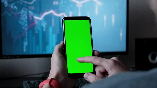 A young man holding a green screen of a mobile phone in the hands of the graphs