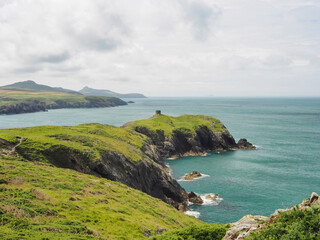 View from the cliff top near Abereiddy over the dramatic coastline with round stone tower on the headland above the Blue Lagoon, a former slate quarry, Pembrokeshire Coast National Park, Wales, UK