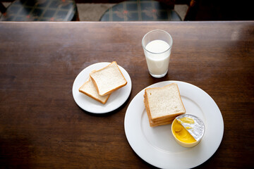Bread slice with butter put on white dish with a glass of milk put on the table, breakfast food concept