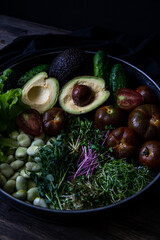 Metal tray full of fresh vegetables: colorful tomatoes , cucumbers, beans, avocado, salad leaves, micro greens.