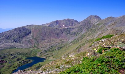 Fototapeta na wymiar Étangs et lacs des Bouillouses avec le massif du Carlit dans les Pyrénées Orientales en France avec de l'eau et du ciel bleu et des randonneurs