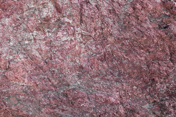 Close up view onto rough surface of red granite with its granular and phaneritic in texture