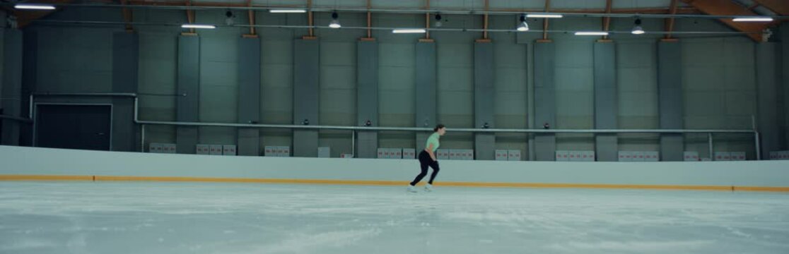 Professional teenager female ice figure skater practicing jumps on the rink. Shot on RED cinema camera with 2x Anamorphic lens, 75 FPS slow motion