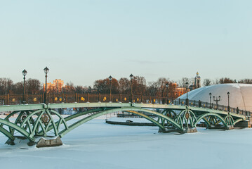 Green openwork metal arcuate bridge over a frozen reservoir in Tsaritsino park in Moscow in Russia. Winter scenery landscape