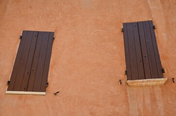 Two brown wooden shutters in an ocher house, Roussillon, Provence, France