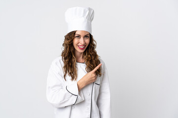 Young chef woman isolated on white background pointing to the side to present a product