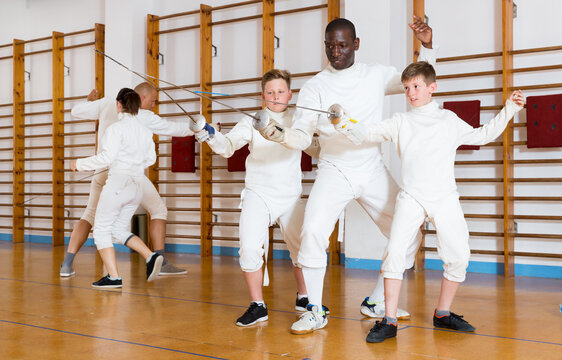 Fencing instructor explaining to young fencers effective movements and techniques in the training room