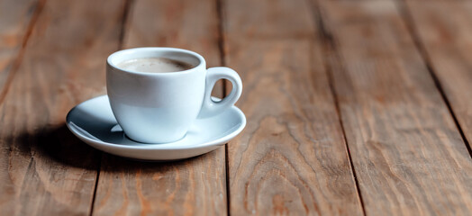 Cup of coffee on an old wooden table. White ceramic. Aromatic coffee with foam